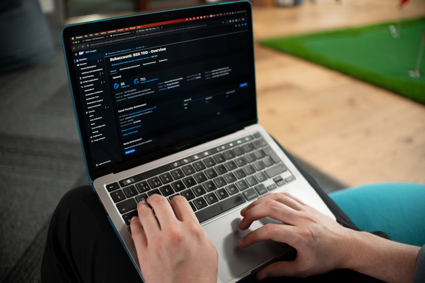 Manos escribiendo en un notebook con paneles de datos superpuestos en pantalla
